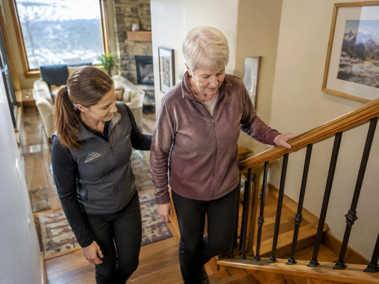 Physical therapist helping a senior woman climb the stairs in her Littleton home